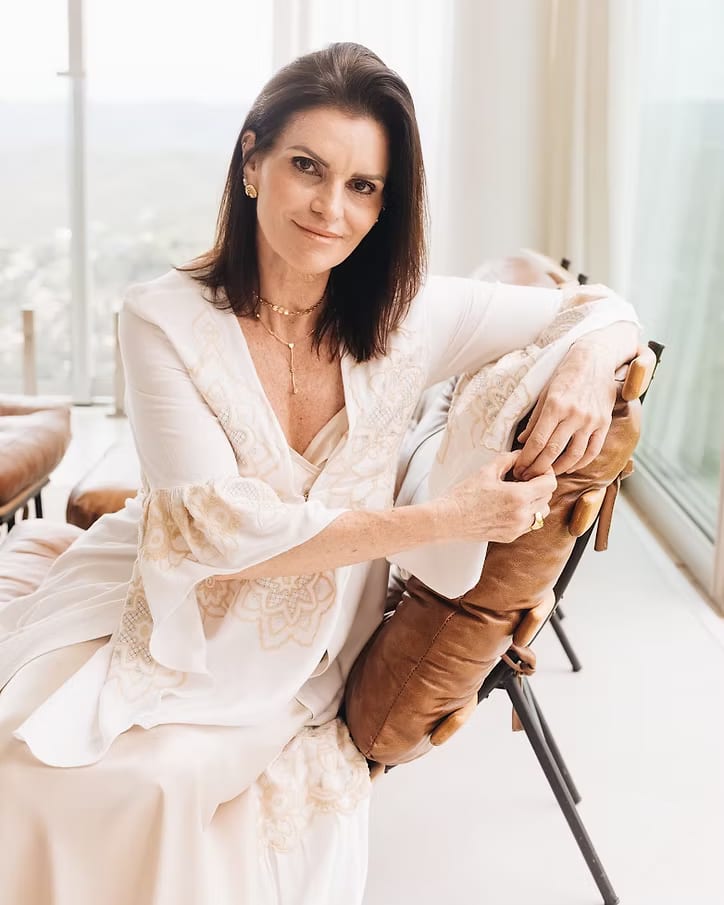 Fátima Myrrha, terapeuta transpessoal, sentada em uma sala clara e sorrindo